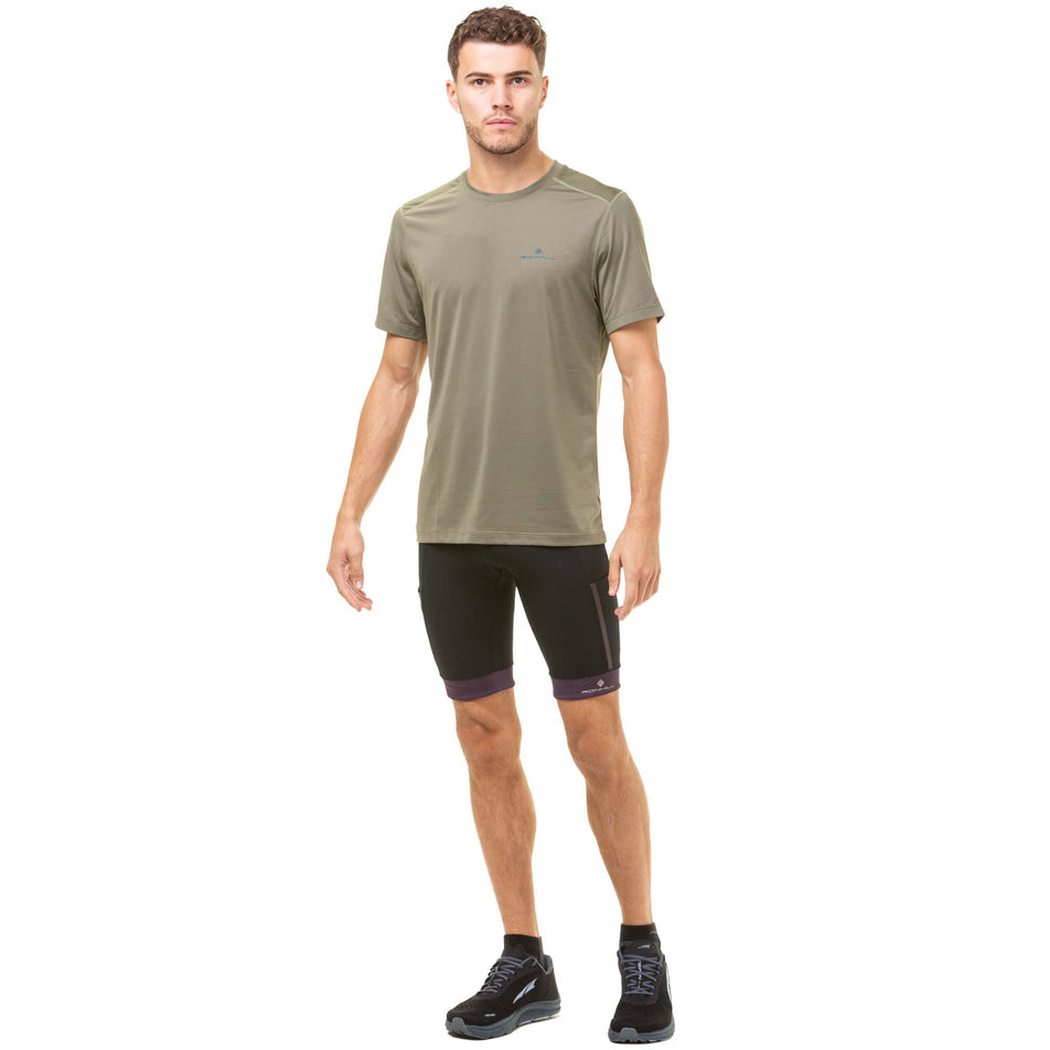 Front view of a model wearing a Ronhill Men's Tech S/S Tee in the Woodland/Deep Lagoon colourway. Model also wearing black and purple Ronhill running shorts, along with black Altra running shoes. (8032261898402)