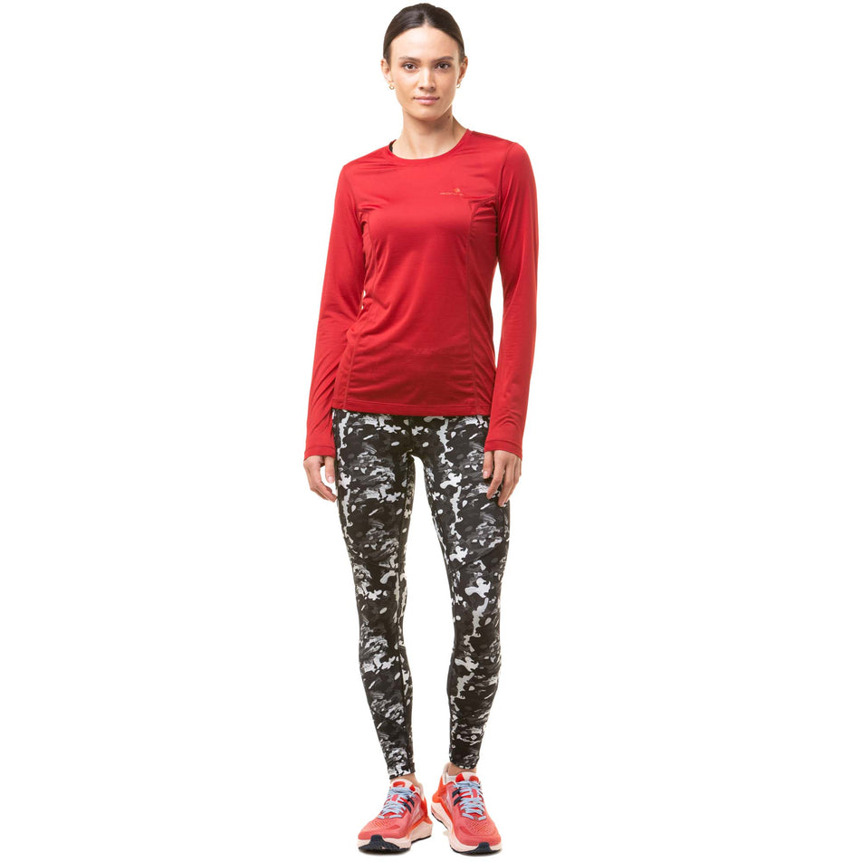 Front view of a model wearing a Ronhill Women's Tech L/S Tee in the Jam/Flame colourway. Model also wearing Ronhill running leggings and Altra running shoes.  (8047364472994)