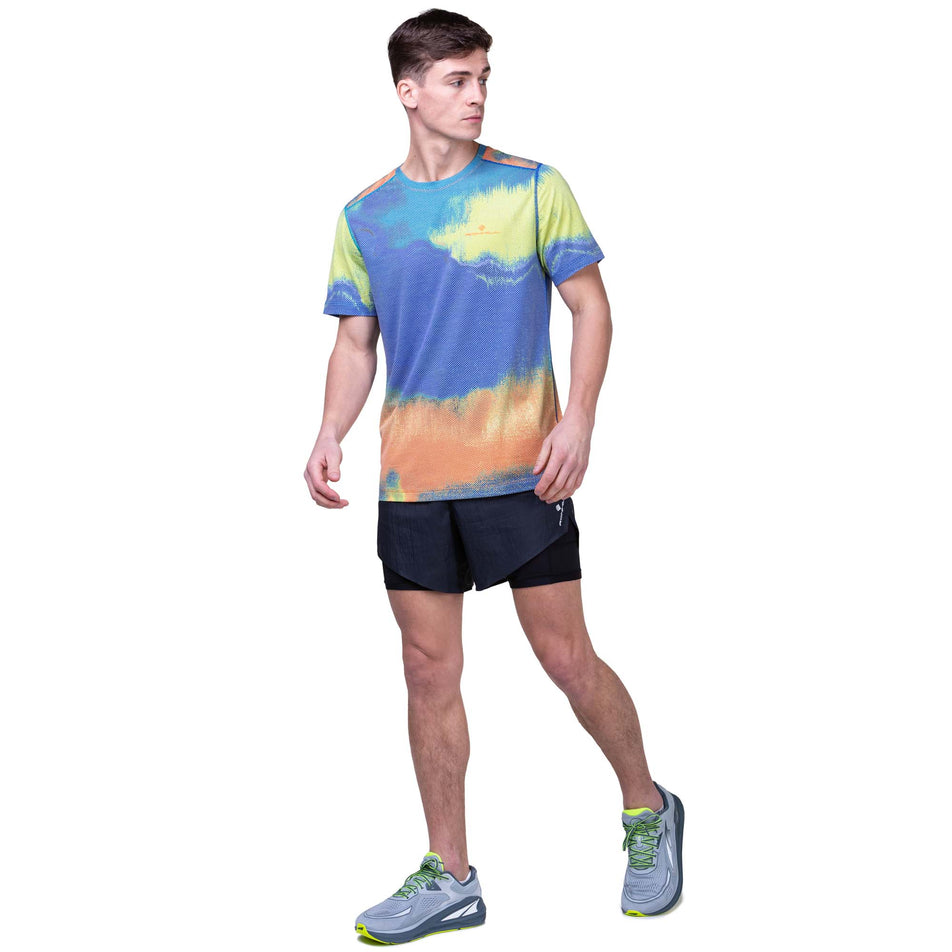 Front view of a model wearing a Ronhill Men's Tech Golden Hour Tee in the Multi Rave colourway. Model is also wearing Ronhill running shorts and Altra running shoes. (8160879149218)