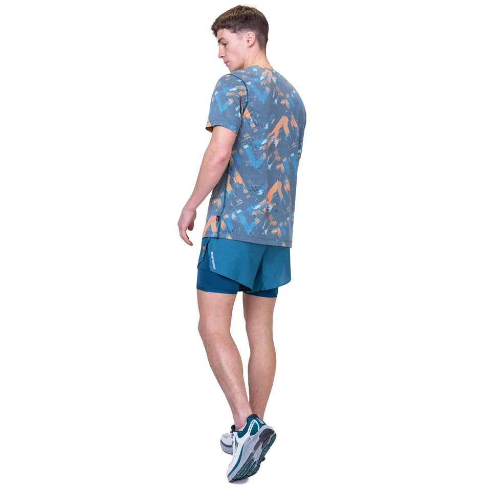 Back view of a model wearing the Ronhill Men's Tech Golden Hour Tee in the Legion Blue Chevron colourway. Model is also wearing Ronhill running shorts and Altra running shoes. (8159267422370)