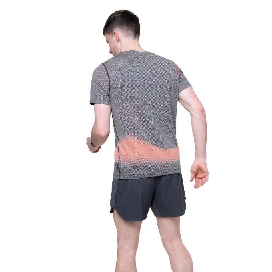 Back view of a model wearing the Ronhill Men's Tech Golden Hour S/S Tee in the Ronhill Red Motion colourway.