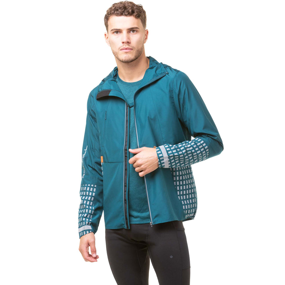 Front view of a model wearing a Ronhill Men's Tech Afterhours Jacket in the Deep Lagoon/Copper Reflect colourway. Jacket is unzipped, but the front sides of the jacket are joined together via a fastener at the chest.  (8047865364642)
