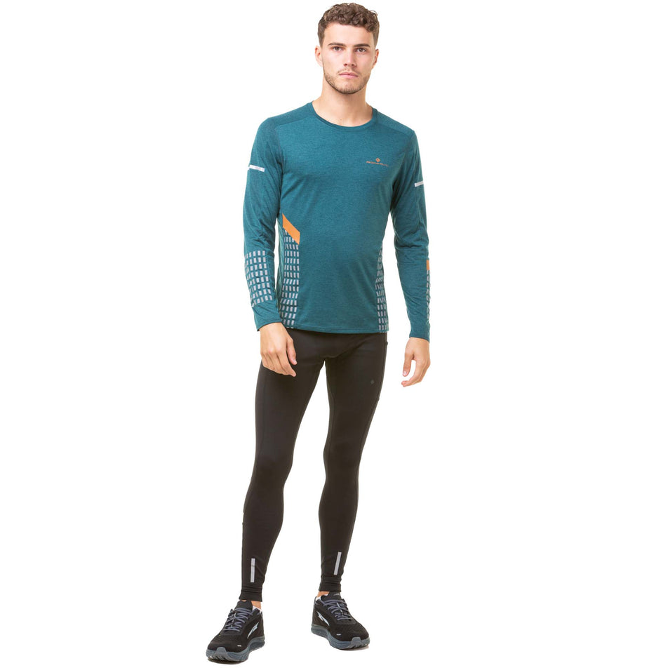 Front view of a model wearing a Ronhill Men's Tech Afterhours L/S Tee in the Deep Lagoon/Copper Reflect colourway. Model also wearing Ronhill running tights and Altra running shoes. (8048083337378)
