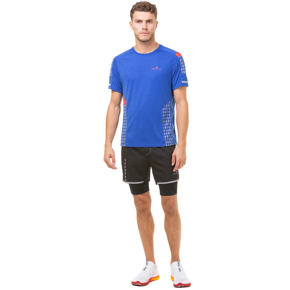 Front view of a model wearing a Ronhill Men's Tech Afterhours S/S Tee in the Cobalt/Flame/Reflect colourway. Model is also wearing Ronhill running shorts and Altra running shoes. (8048091725986)