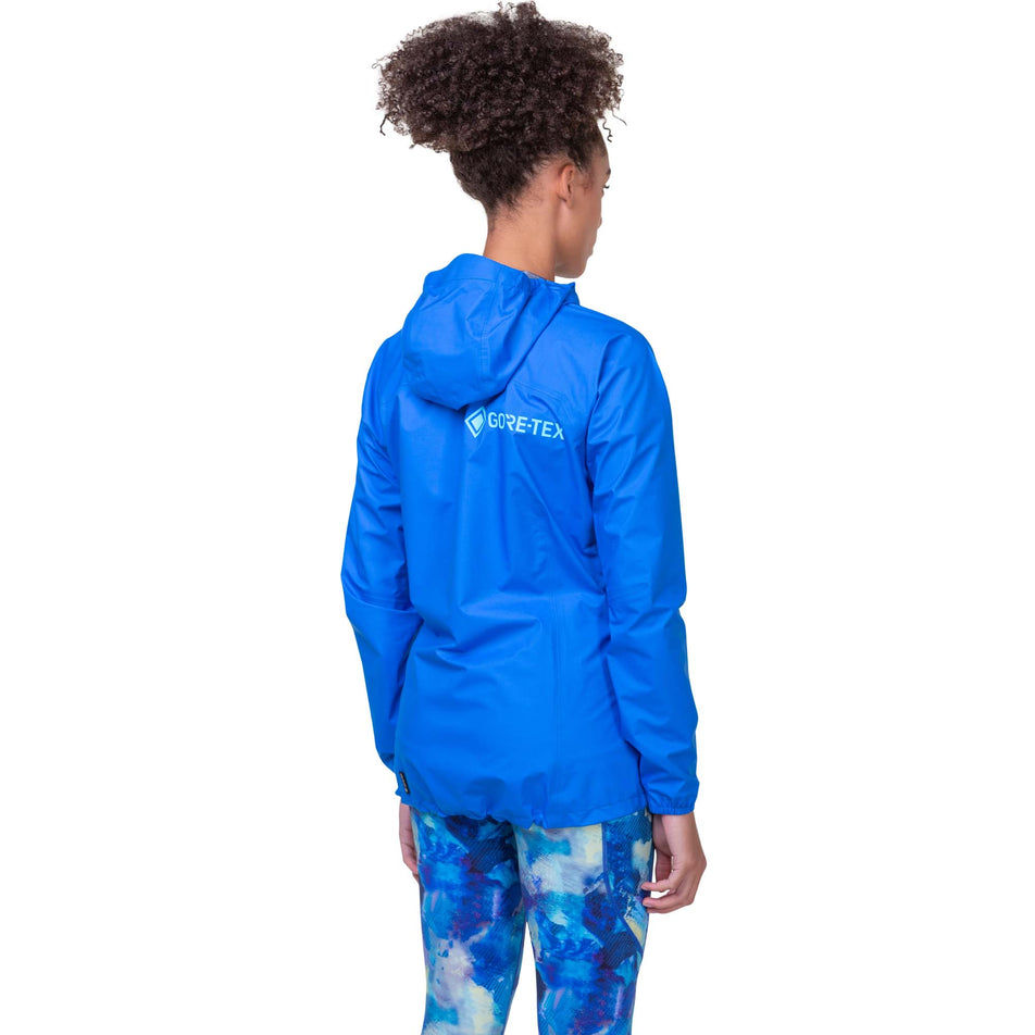 Back view of a model wearing the Ronhill Women's Tech GORE-TEX Mercurial Jacket in the Electric Blue/Aquamint colourway. Model is also wearing Ronhill leggings. (8160854769826)