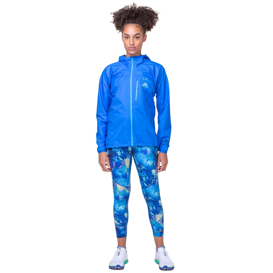 Front view of a model wearing the Ronhill Women's Tech GORE-TEX Mercurial Jacket in the Electric Blue/Aquamint colourway. Model is also wearing Ronhill leggings and Altra running shoes.. (8160854769826)