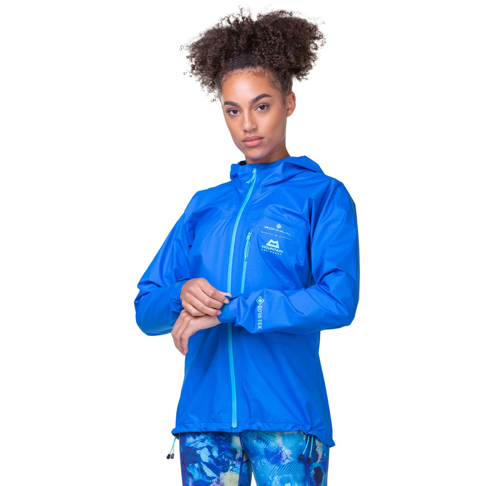 Front view of a model wearing the Ronhill Women's Tech GORE-TEX Mercurial Jacket in the Electric Blue/Aquamint colourway. Model is also wearing Ronhill leggings.  (8160854769826)