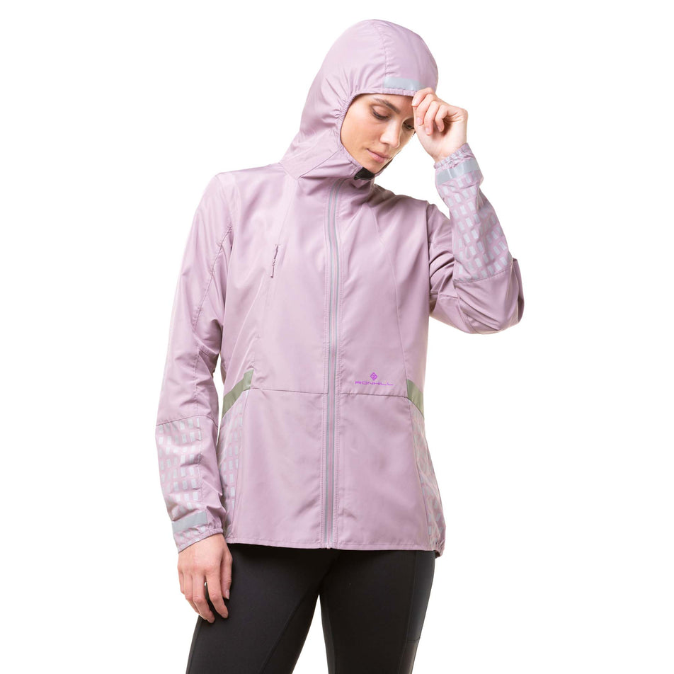 Front view of a model wearing a Ronhill Women's Tech Afterhours Jacket in the Stardust/Thistle/Reflect colourway. Jacket being worn with the hood up.  (8019199557794)