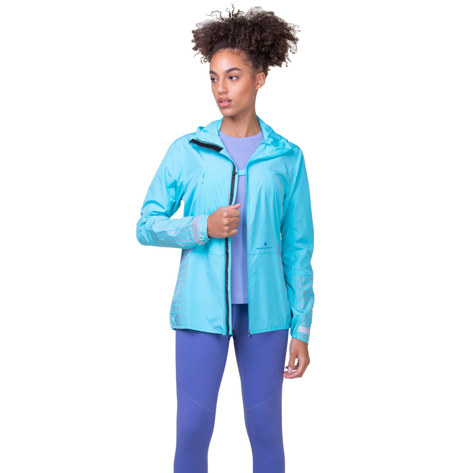 Front view of a model wearing the Ronhill Women's Tech Afterhours Jacket in the Aquamint/Reflect colourway. Model is also wearing Ronhill leggings. (8160853983394)