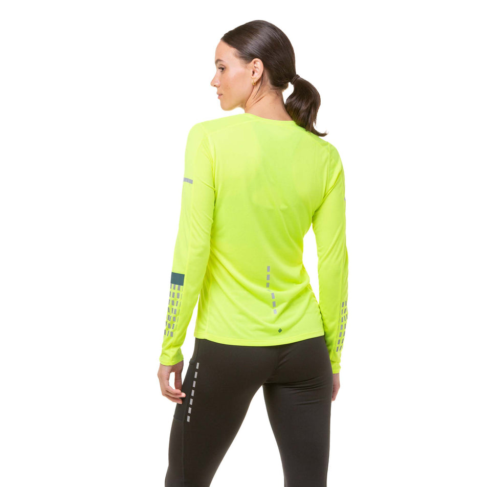Back view of a model wearing a Ronhill Women's Tech Afterhours L/S Tee in the Fluo Yellow/Deep Lagoon/Reflect colourway.  (8023196041378)