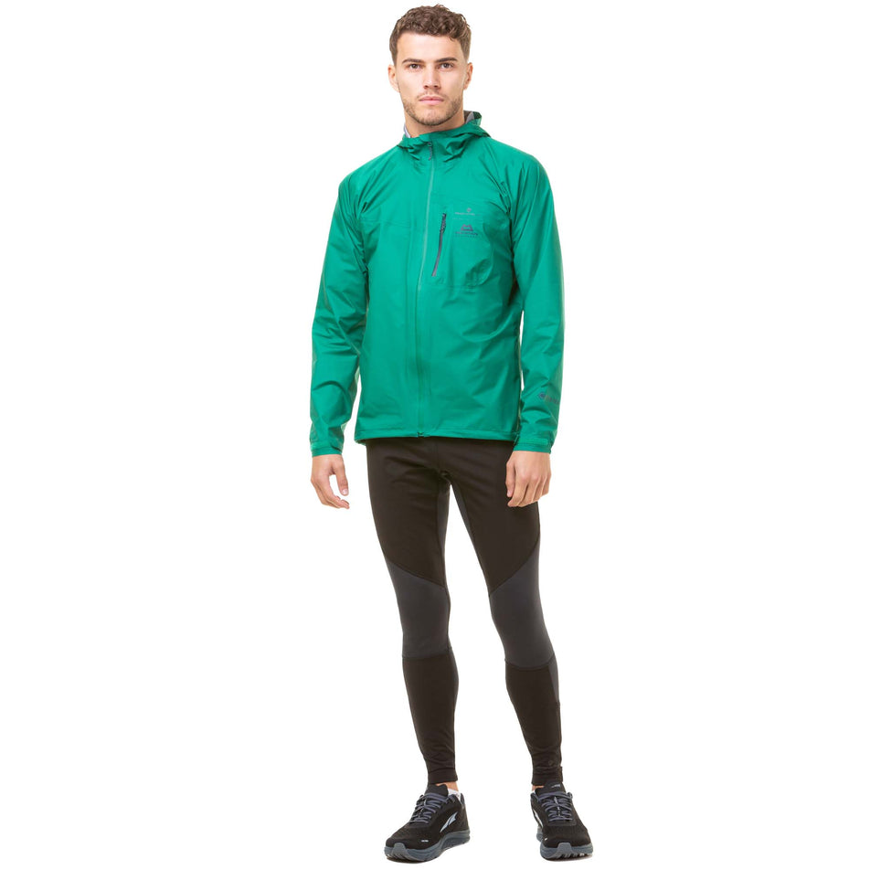 Front view of a model wearing a Men's Tech GORE-TEX Mercurial Jacket in the Lawn/Deep Lagoon colourway. Model is also wearing Ronhill running tights and Altra running shoes. (8048099786914)