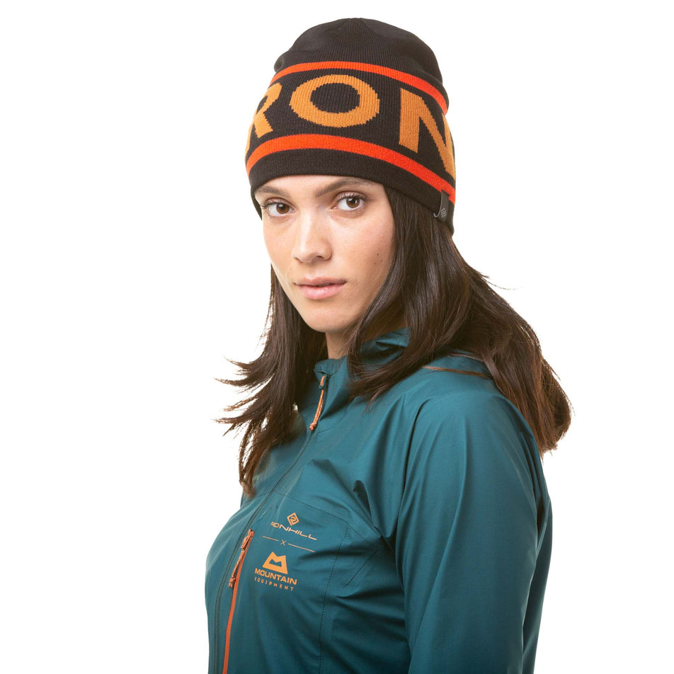 Front view of a model wearing a Ronhill Unisex Tribe Running Beanie in the Black/Flame/Copper colourway (8048576102562)