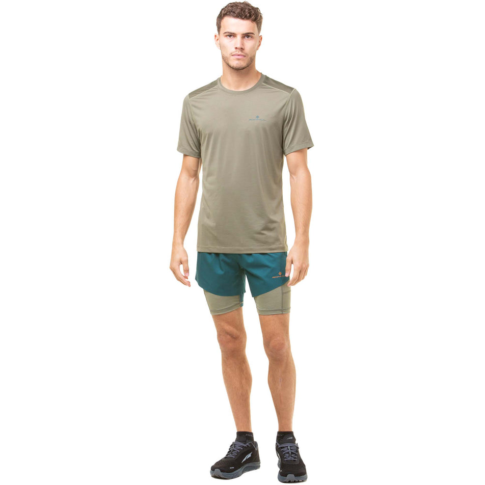 Front view of a model wearing a pair of Ronhill Men's Tech Distance Twin Shorts in the Deep Lagoon/Woodland colourway. Model is also wearing a Ronhill running t-shirt and Altra running shoes. (8048123084962)