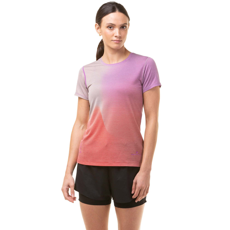 Front view of a model wearing a Ronhill Women's Tech Goldenhour Tee in the Jam/Stardust Merge colourway. Model is also wearing black Ronhill running shorts. (8031399248034)