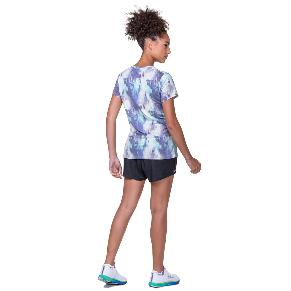 Back view of a model wearing a Ronhill Women's Tech Golden Hour Tee in the Multi Illusion colourway. Model is also wearing Ronhill running shorts and Altra running shoes. (8158817616034)