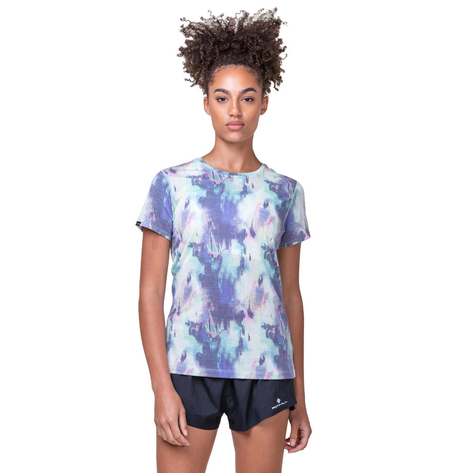Front view of a model wearing a Ronhill Women's Tech Golden Hour Tee in the Multi Illusion colourway. Model is also wearing Ronhill running shorts. (8158817616034)