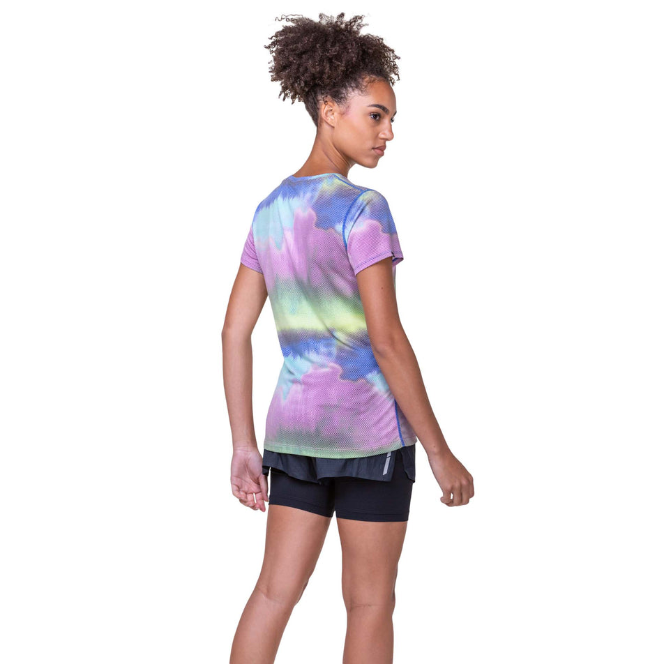 Back view of a model wearing a Ronhill Women's Tech Golden Hour Tee in the Multi Mirage colourway. Model is also wearing Ronhill running shorts. (8159330271394)