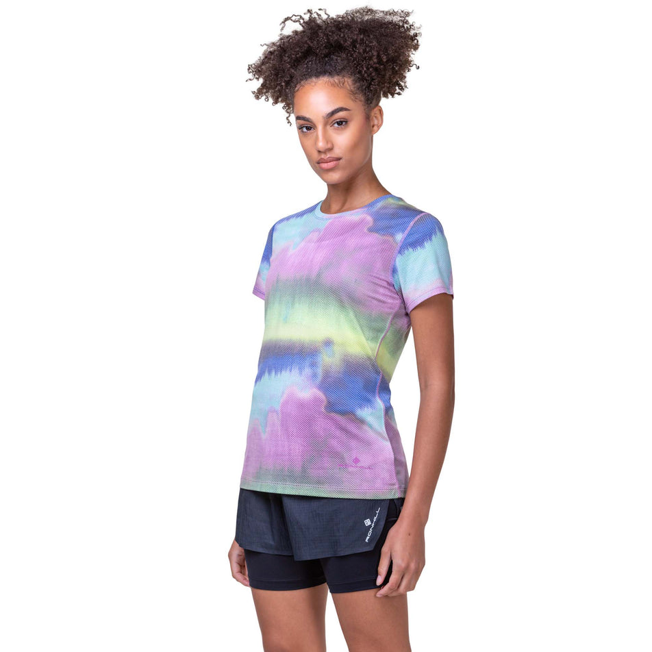 Front view of a model wearing a Ronhill Women's Tech Golden Hour Tee in the Multi Mirage colourway. Model is also wearing Ronhill running shorts. (8159330271394)