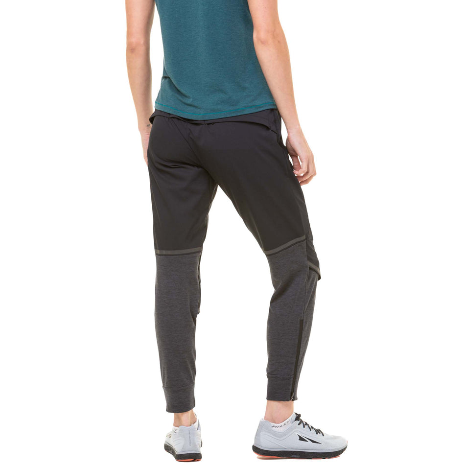 Back view of a model wearing a pair of Ronhill Women's Tech Flex Pants in the Black/Charcoal Marl colourway. Model also wearing a Ronhill running t-shirt and a pair of Altra running shoes. (8047394554018)