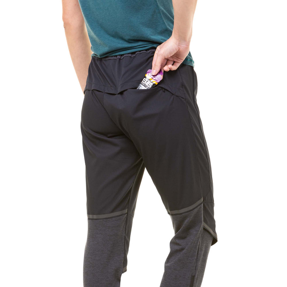 A model demonstrating that an energy gel can be stored in the back zipped pocket of a pair of Ronhill Women's Tech Flex Pants (8047394554018)