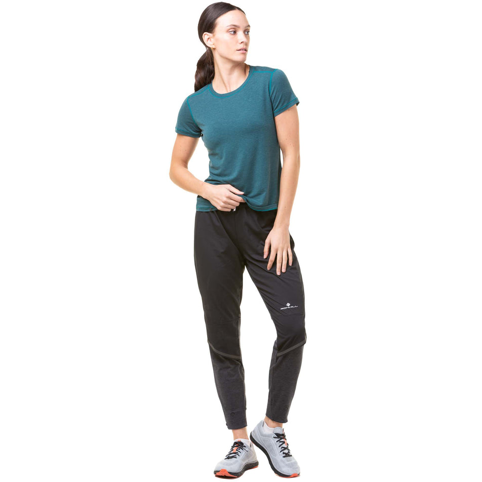 Front view of a model wearing a pair of Ronhill Women's Tech Flex Pants in the Black/Charcoal Marl colourway. Model also wearing a Ronhill running t-shirt and a pair of Altra running shoes. (8047394554018)