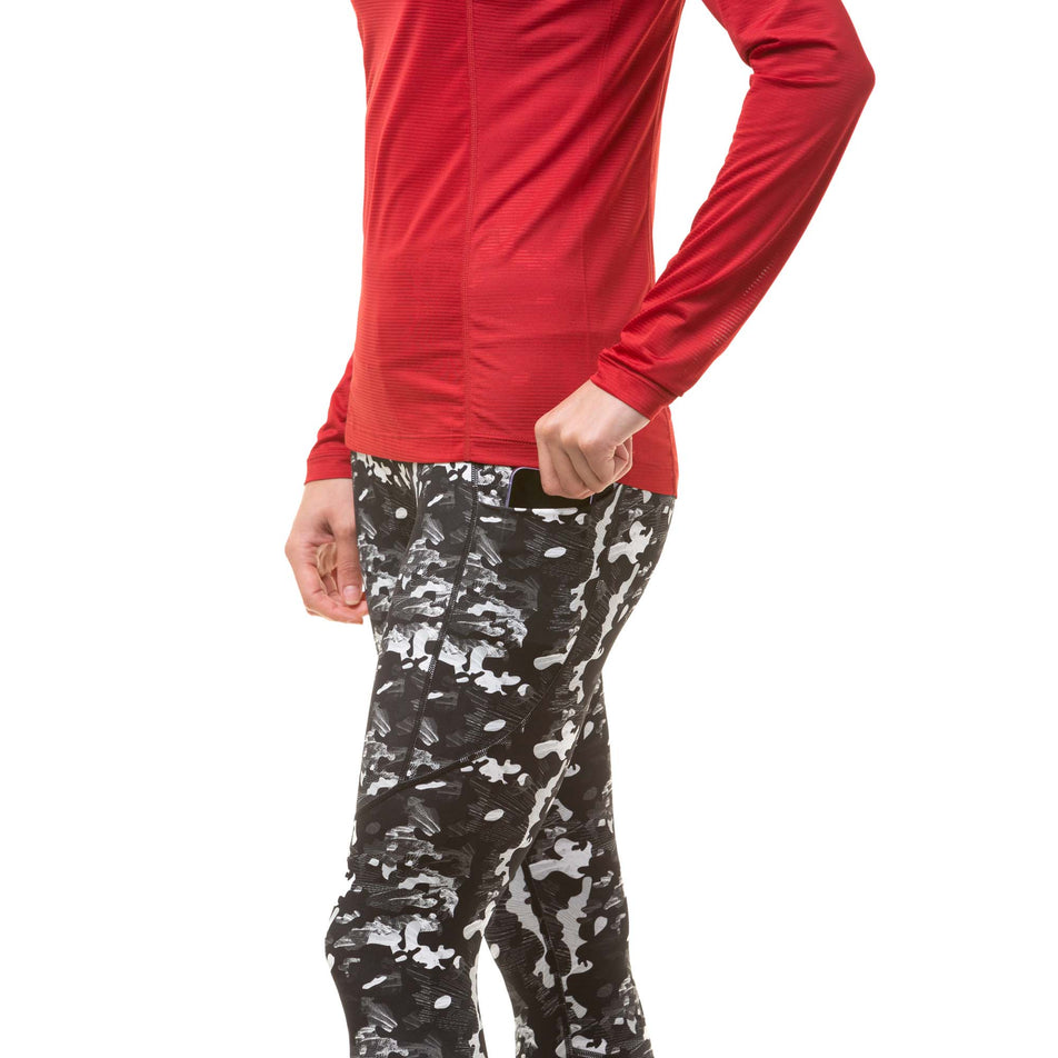 A model demonstrating that a mobile phone can be stored in the side stretch pocket on the outside of the left thigh section of a pair of Ronhill Women's Tech Tights (8047451832482)