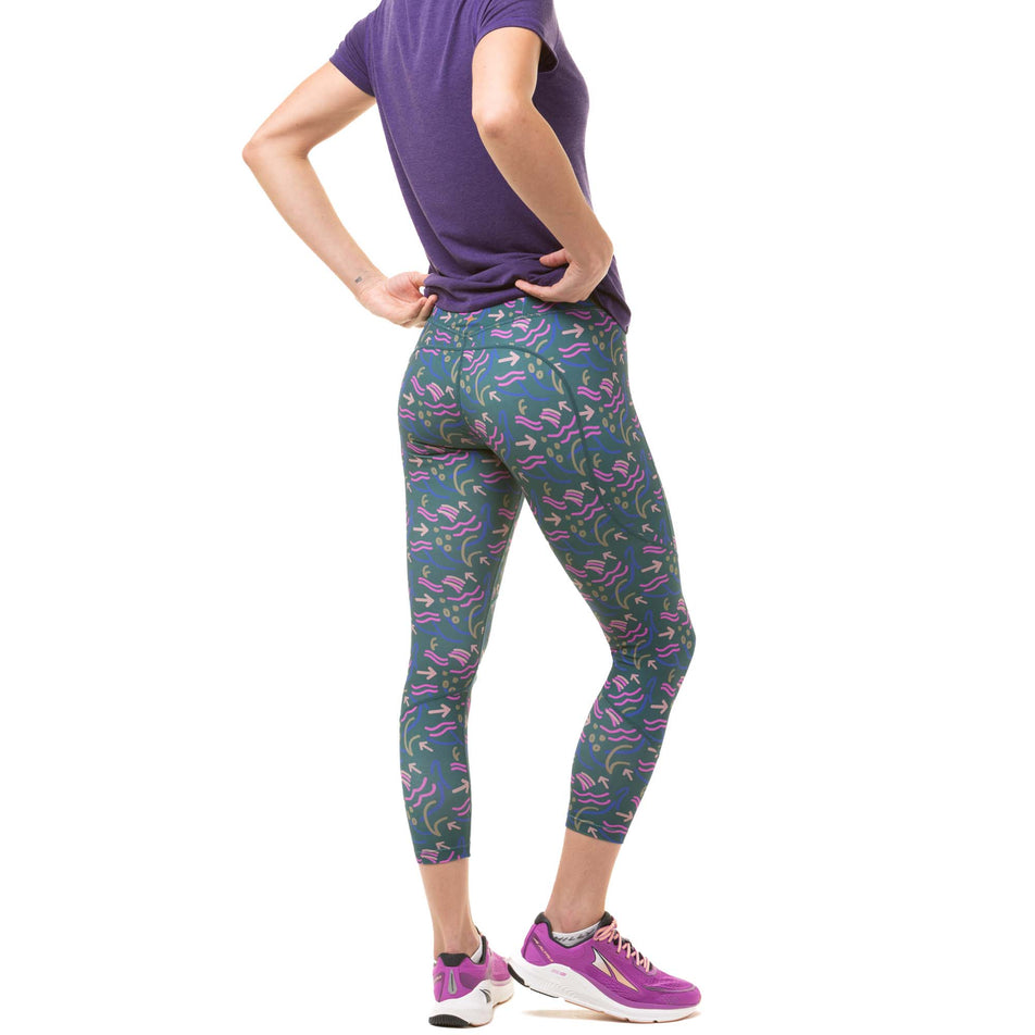 Back view of a model wearing a pair of Ronhill Women's Tech Crop Tights in the Deep Lagoon Direction colourway. Model is also wearing a Ronhill running t-shirt and Altra running shoes. (8047471526050)