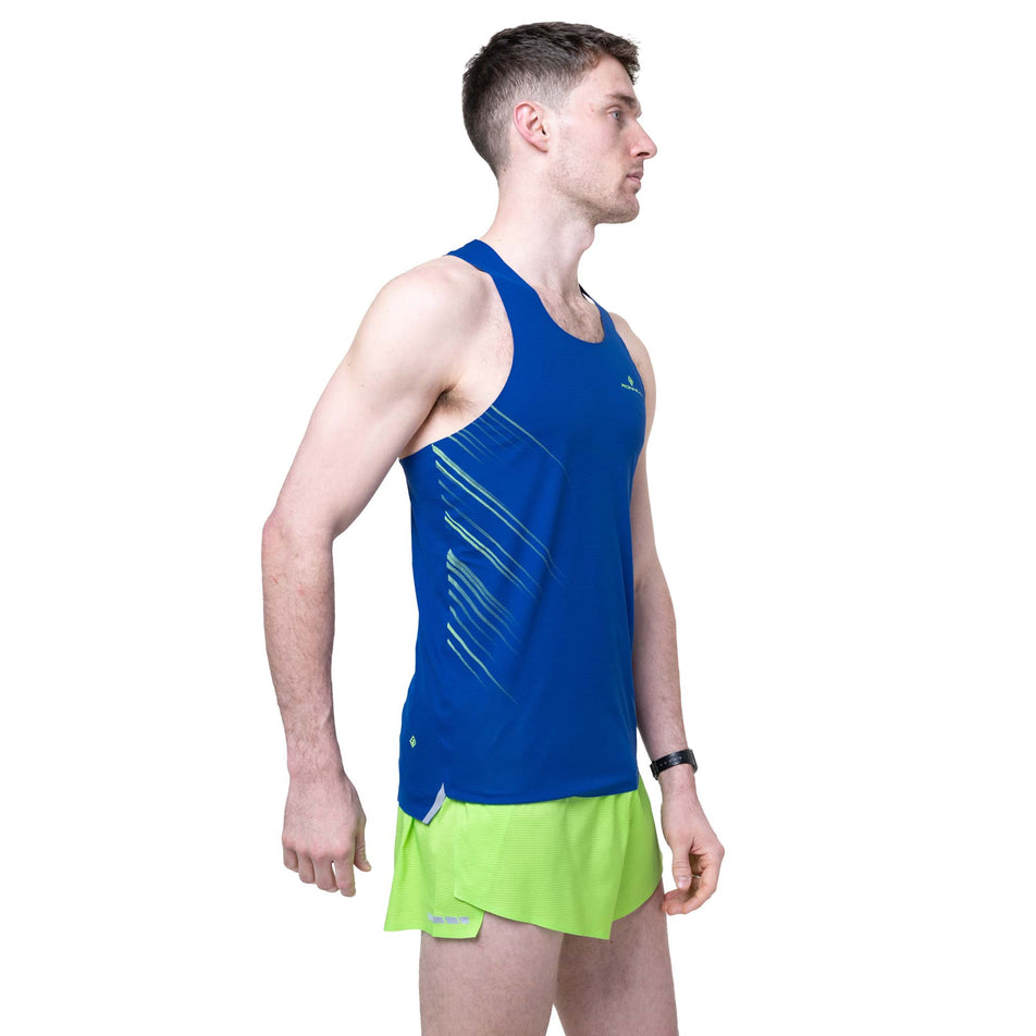 Angled view of a model wearing the Ronhill Men's Tech Race Short in the Fluo Green/Dark Cobalt colourway.