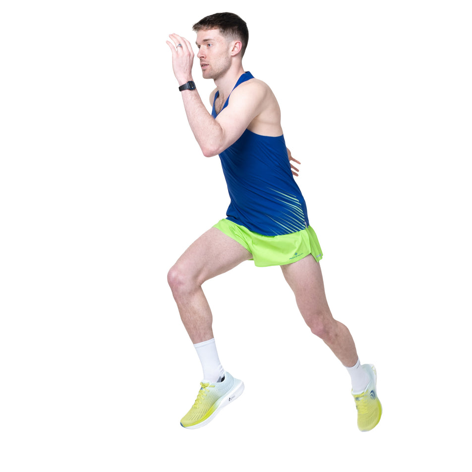 Angled view of a model wearing the Ronhill Men's Tech Race Vest in the Dark Cobalt/Fluo Green colourway.