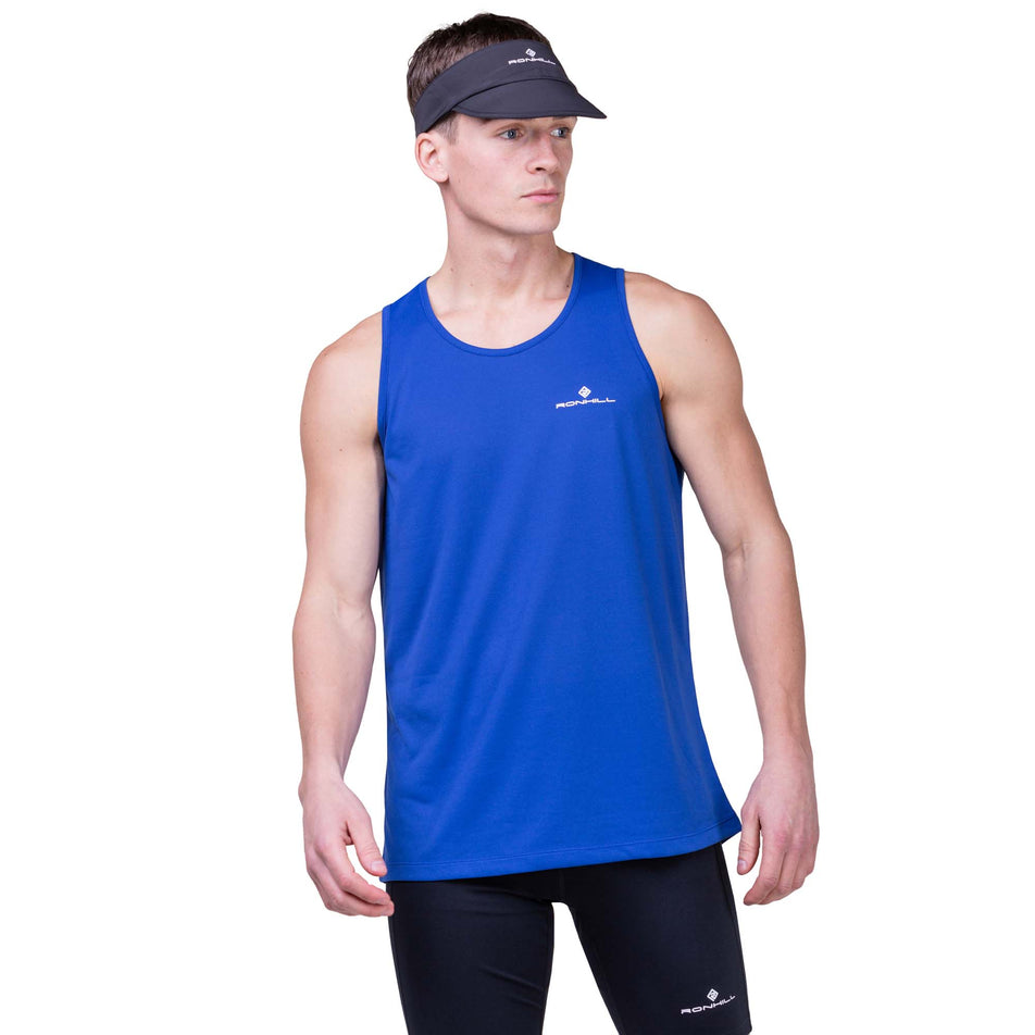 Front view of a model wearing a Ronhill Unisex Sunlight Vizor in the All Black colourway. Model is also wearing a Ronhill top and shorts.  (8160952451234)