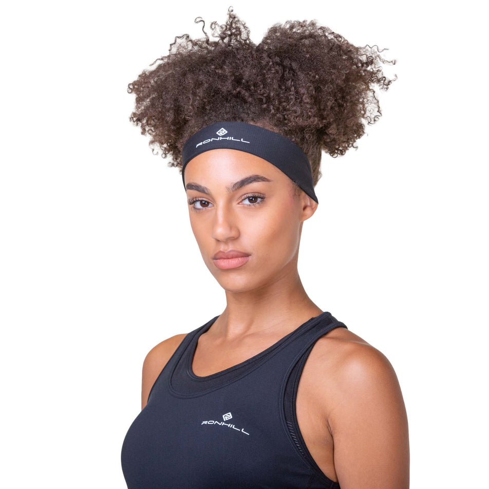 A model wearing a Ronhill Unisex Lightweight Headband in the All Black colourway. Model is also wearing a Ronhill top.  (8160971980962)
