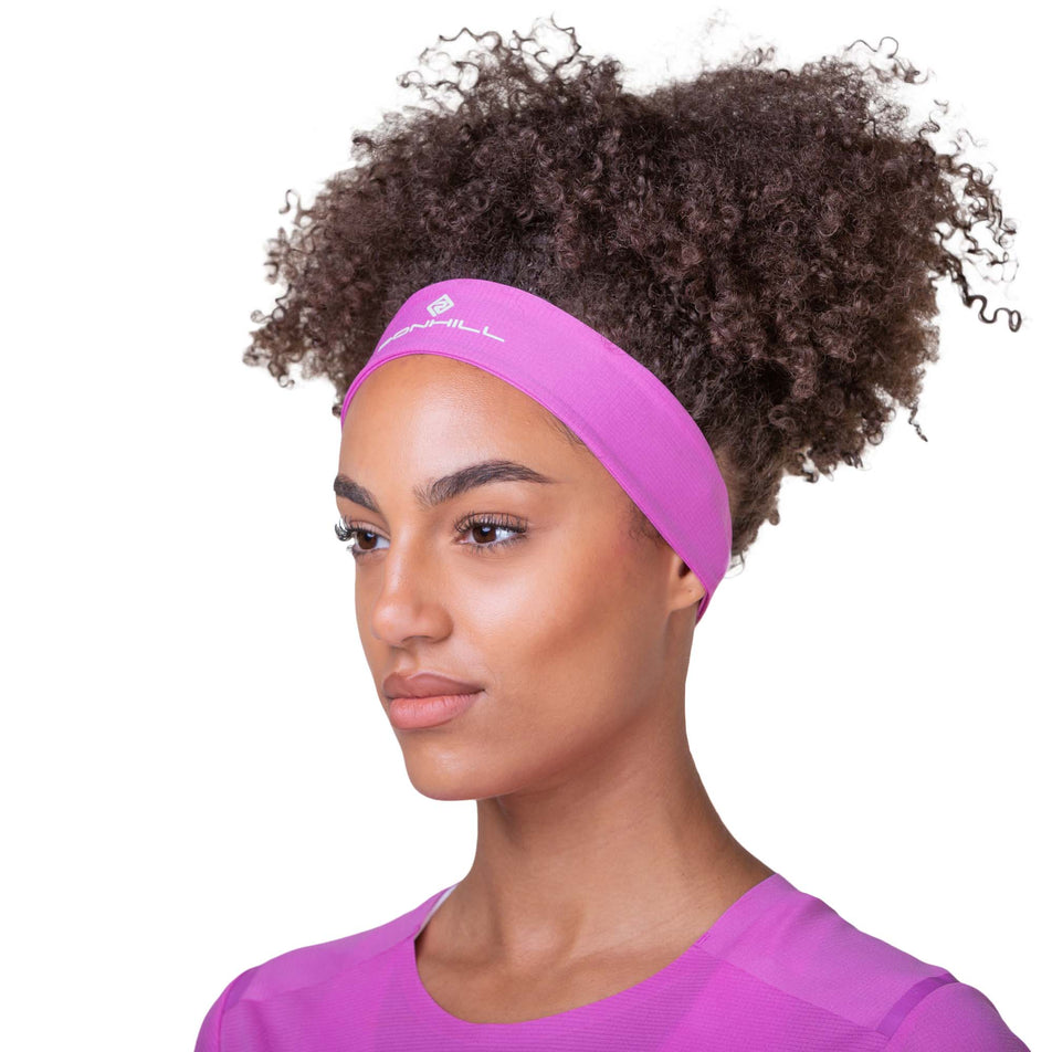 Front view of a model wearing a Ronhill Unisex Lightweight Headband in the Fuchsia/Honeydew colourway. Model is also wearing a Ronhill top. (8160976830626)