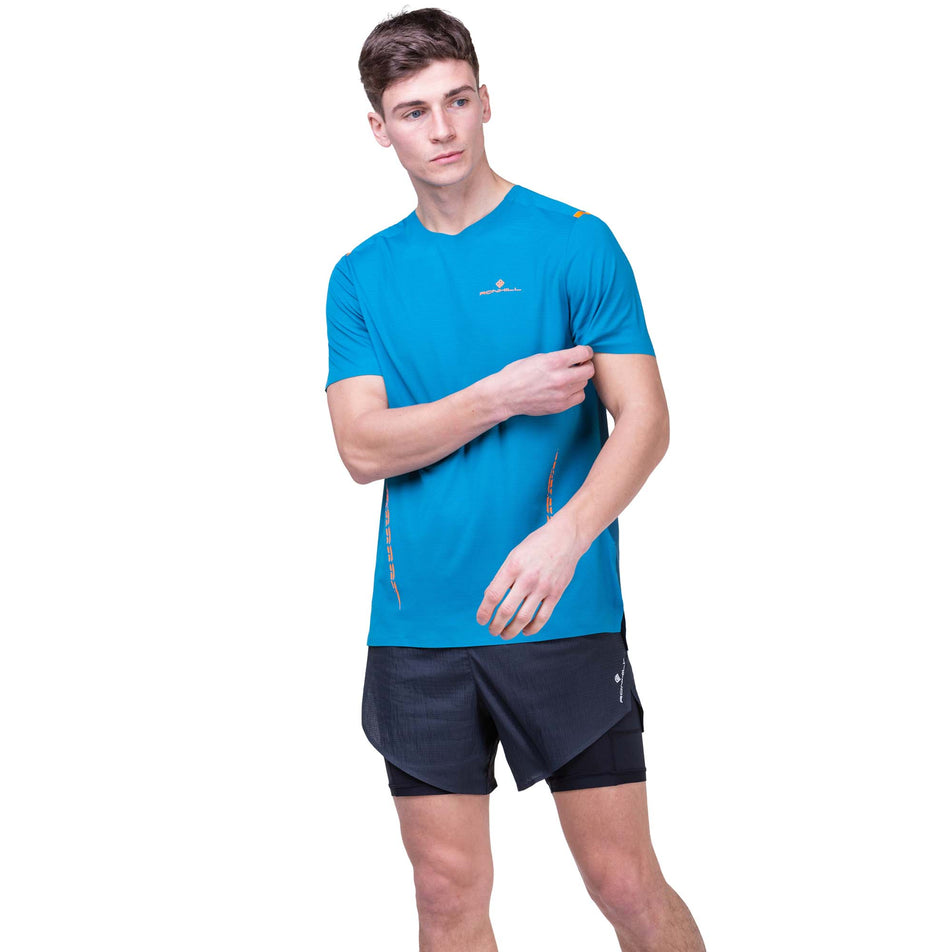 Front view of a model wearing the Ronhill Men's Tech Race S/S Tee in the Petrol/Legion Blue colourway. Model is also wearing Ronhill shorts.  (8160876757154)