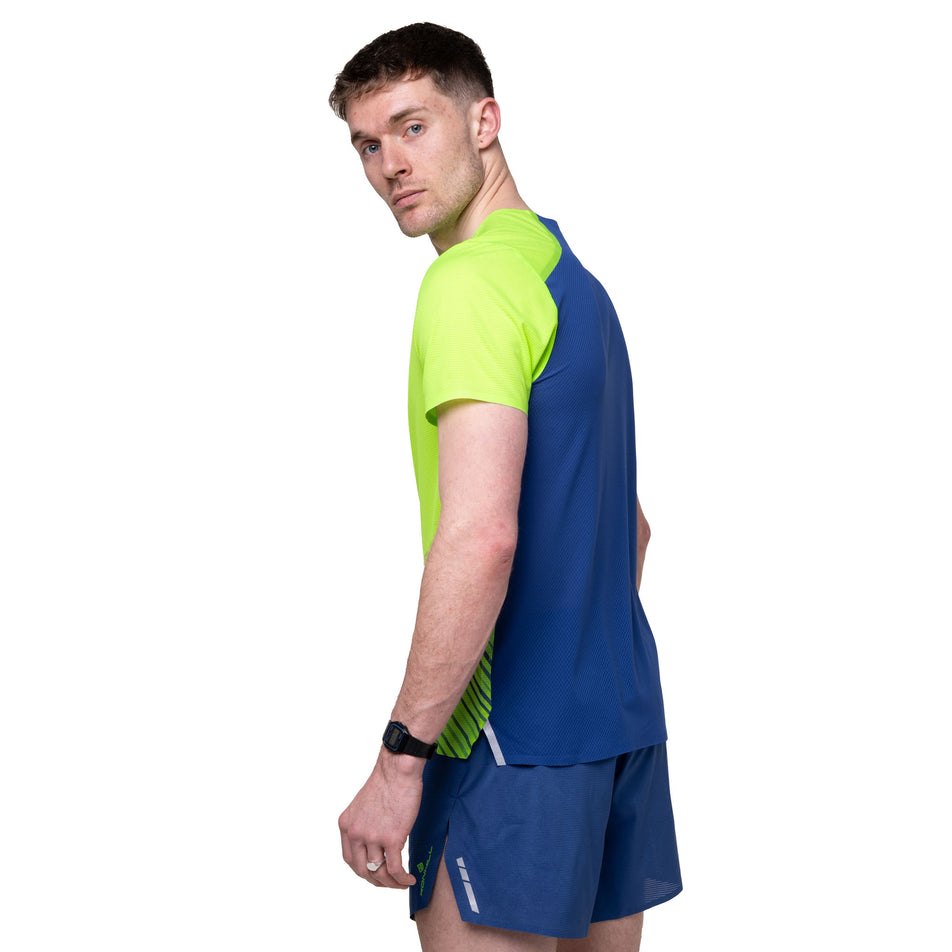 Angled view of a model wearing the Ronhill Men's Tech Race S/S Tee in the Fluo Green/Dark Cobalt colourway.