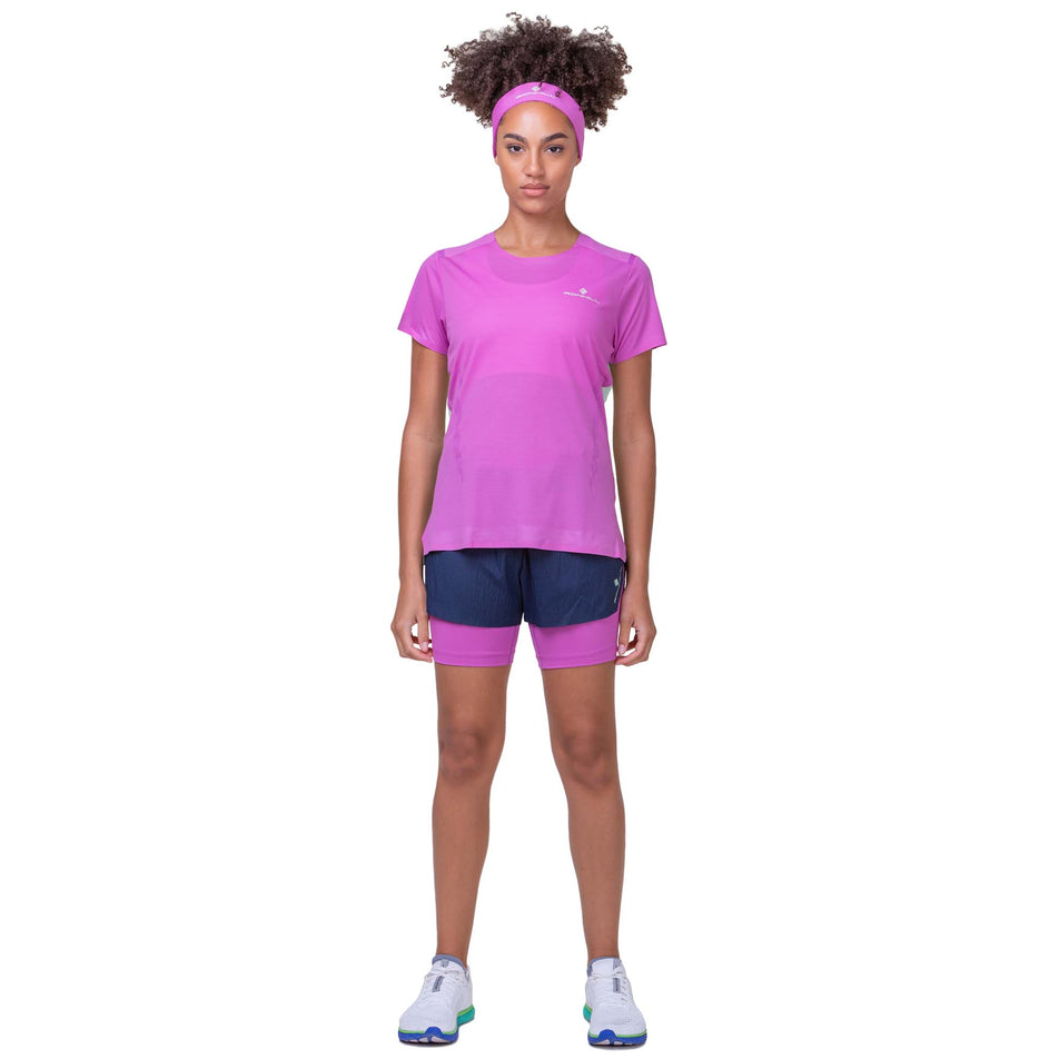 Front view of a model wearing a Ronhill Women's Tech Race S/S Tee in the Fuchsia/Honeydew colourway. Model is also wearing Ronhill shorts and Altra running shoes. (8158803427490)