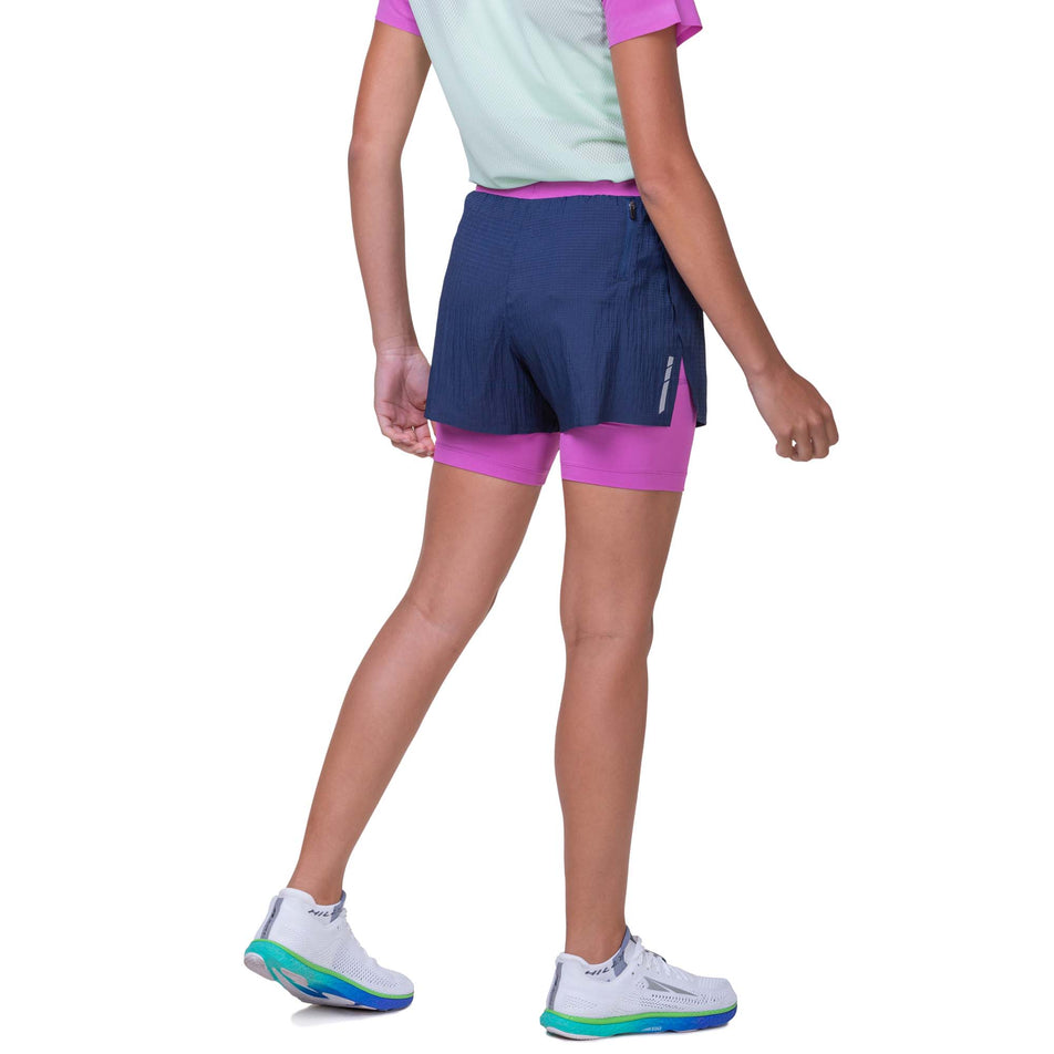 Back view of a model wearing the Ronhill Women's Tech Race Twin Short in the Dark Navy/Fuchsia colourway. Model is also wearing a Ronhill running top. (8159320768674)