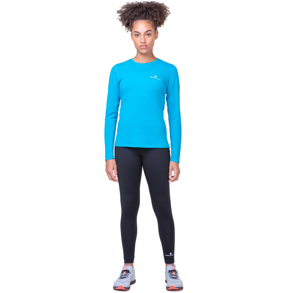 Front view of a model wearing a Ronhill Women's Core L/S Tee in the Azure/Bright White colourway. Model is also wearing Ronhill leggings and Altra running shoes. (8159242420386)