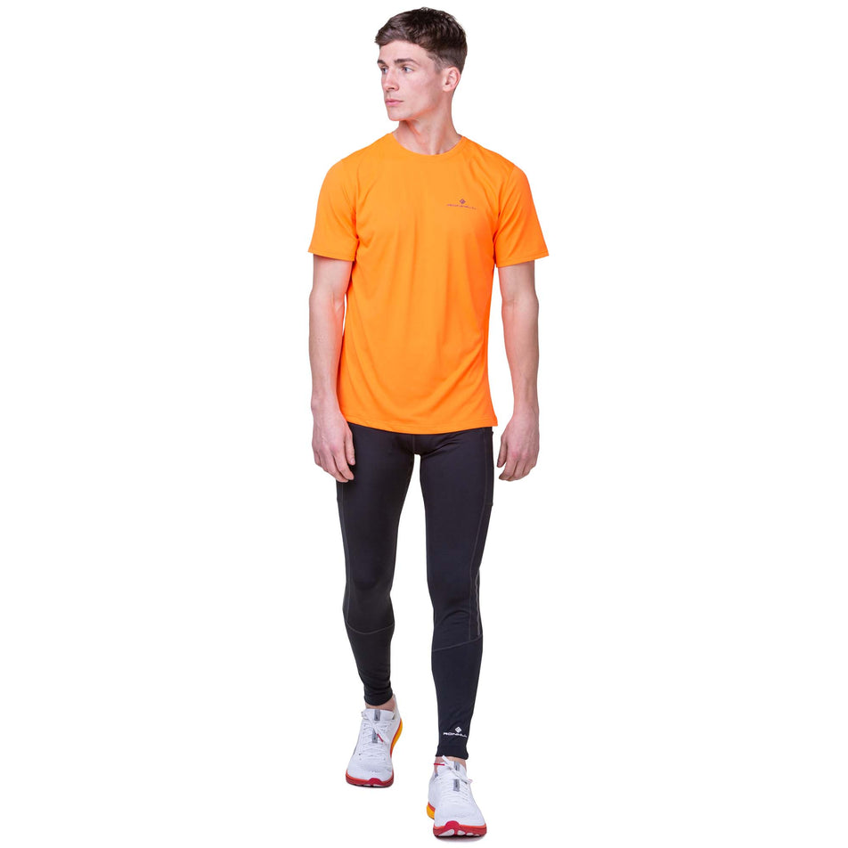 Front view of a model wearing the Ronhill Men's Core S/S Tee in the Fluo Orange/Legion colourway. Model is also wearing Ronhill tights and Altra running shoes.  (8160893599906)