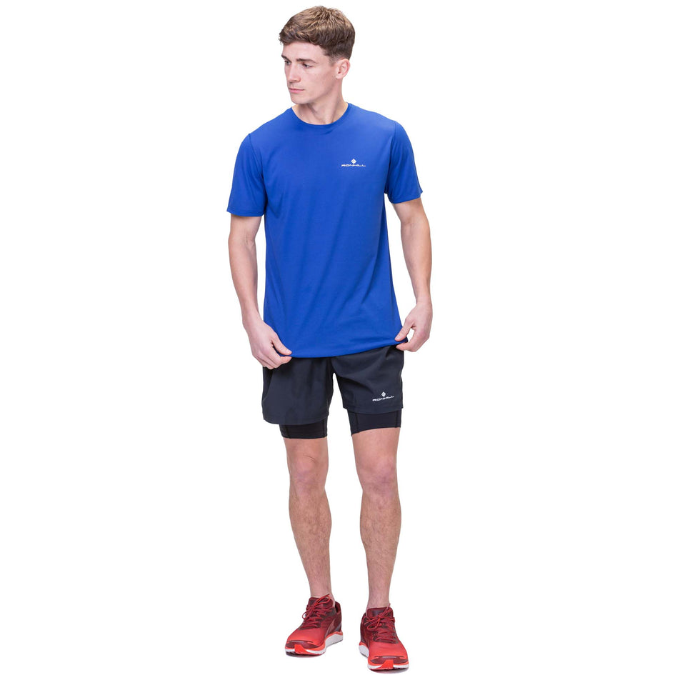 Front view of a model wearing the Ronhill Men's Core Twin Short in the All Black colourway. Model is also wearing a Ronhill t-shirt and Altra running shoes. (8159280201890)