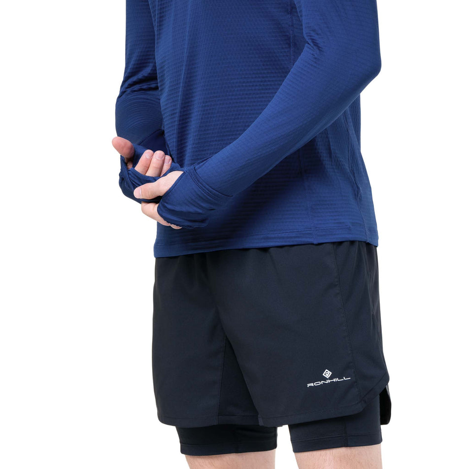 A model demonstrating the thumb loops and over-mitt on the sleeves of the Ronhill Men's Tech Winter 1/2 Zip in the Ocean/Electric Blue colourway. (8748496224418)