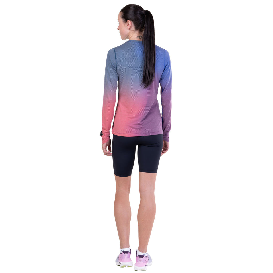 Back view of a model wearing the Ronhill Women's Tech Golden Hour L/S Tee in the Blue Violet Merge colourway.