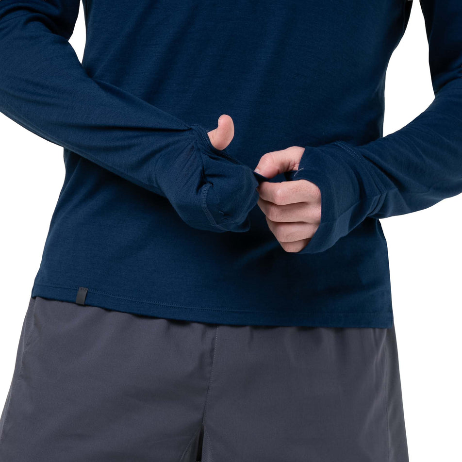 A model demonstrating the overmitt on the sleeve of the Ronhill Men's Tech Merino 1/2 Zip in the Dark Navy/Oxide colourway. (8742863732898)