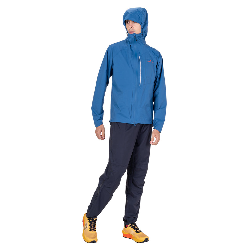Front view of a model wearing the Ronhill Men's Tech Storm Jacket in the Glacier/Ronhill Red colourway.