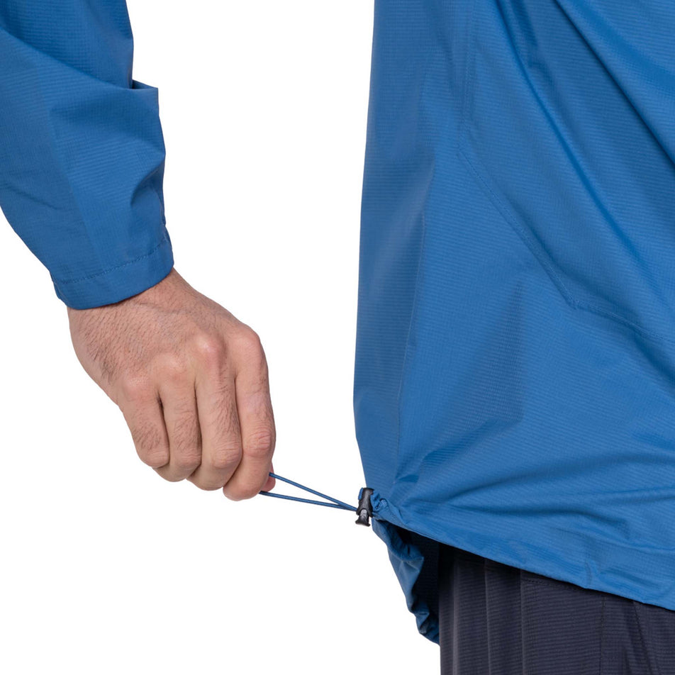 The adjustable toggle on the waist of the Ronhill Men's Tech Storm Jacket in the Glacier/Ronhill Red colourway.