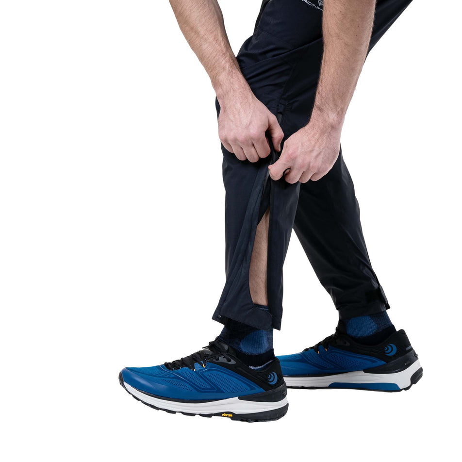 A model demonstrating the ankle zip on the Ronhill Unisex Tech Storm Pant in the All Black colourway. (8748339593378)
