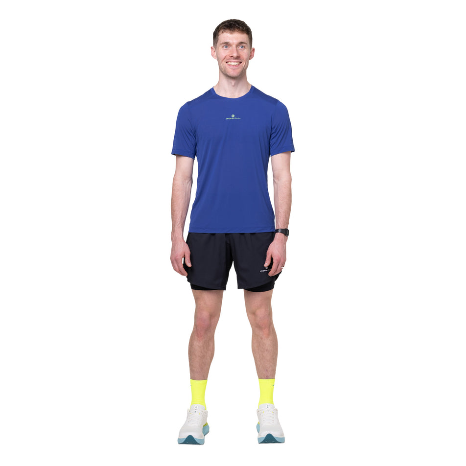 Front view of a model wearing the Ronhill Men's Tech S/S Tee in the Dark Cobalt/Fluo Green colourway.