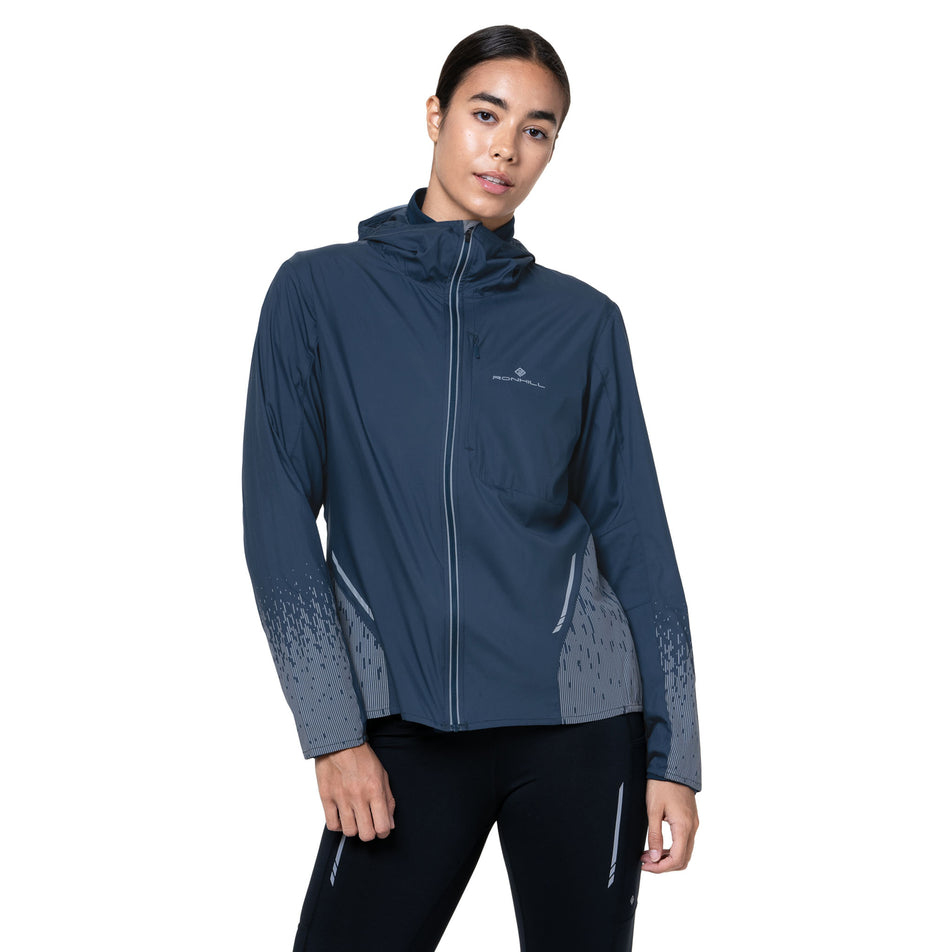 Front view of a model wearing the Ronhill Women's Tech Reflect Jacket in the Dark Navy/Reflect colourway. (8747149787298)