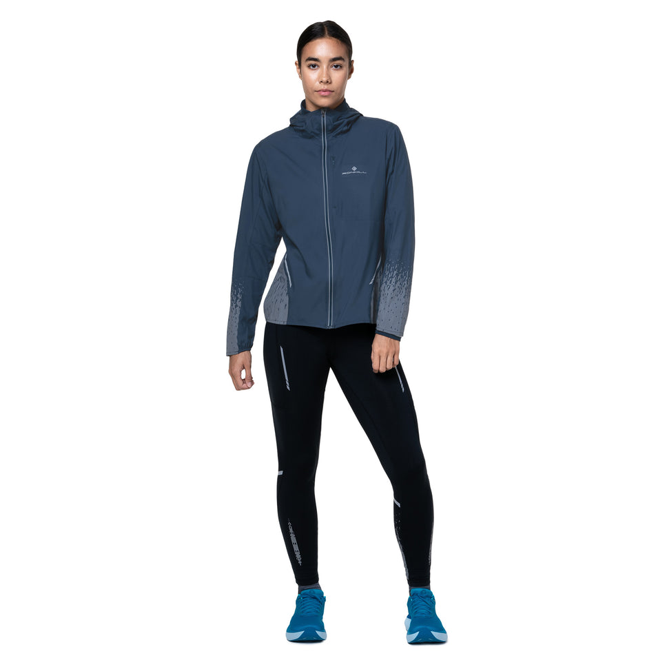 Front view of a model wearing the Ronhill Women's Tech Reflect Jacket in the Dark Navy/Reflect colourway. (8747149787298)