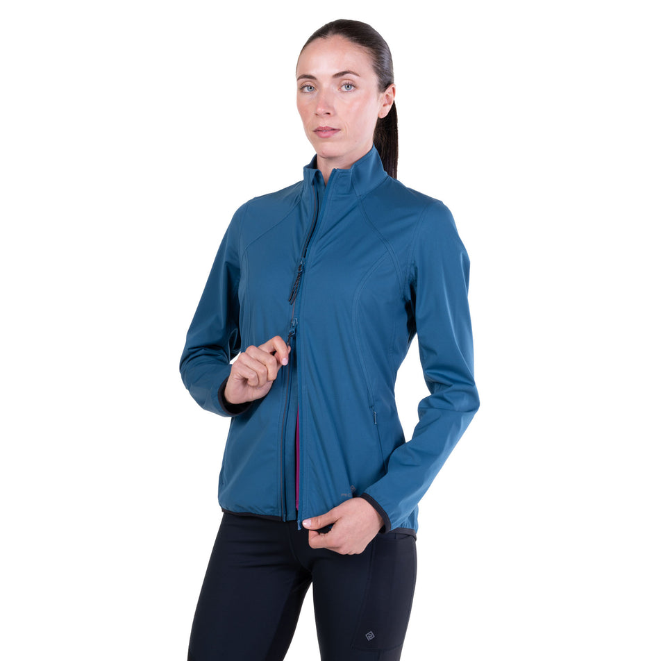 A model demonstrating the two-way zipper on the Ronhill Women's Tech Wind-Block Jacket in the Legion Blue colourway.