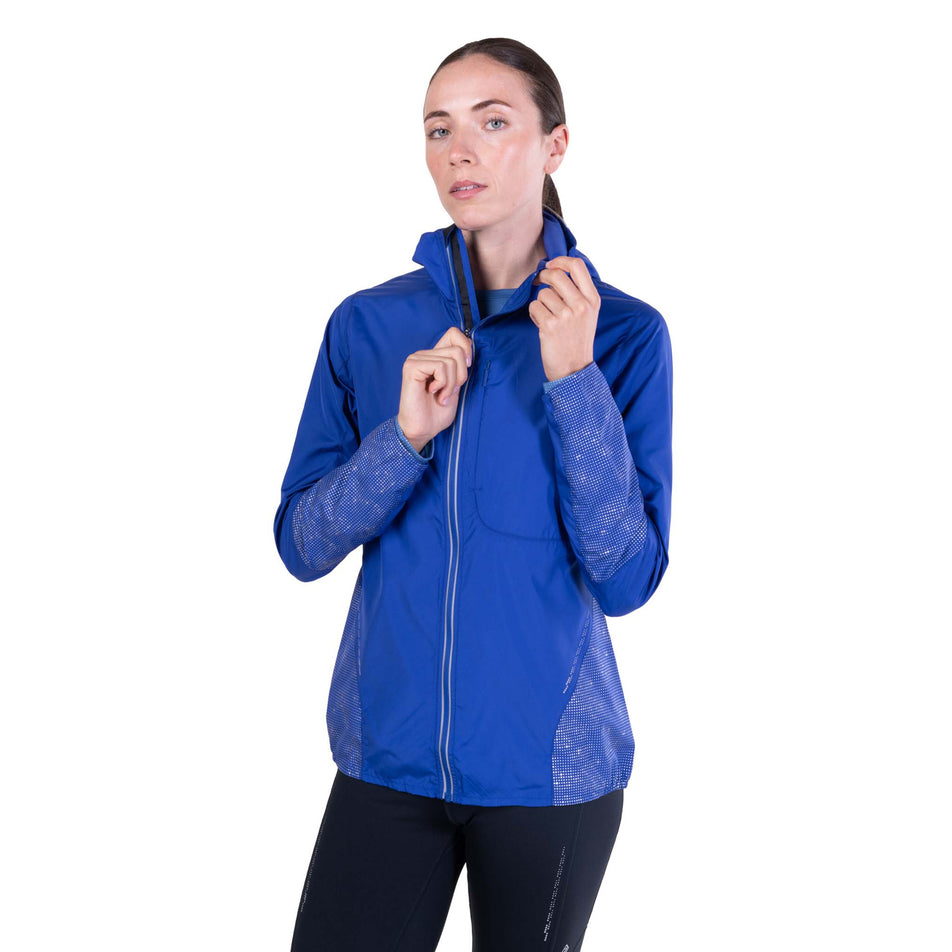 Front view of a model wearing the Ronhill Women's Tech Reflect Jacket in the Blue Violet/Reflect colourway.